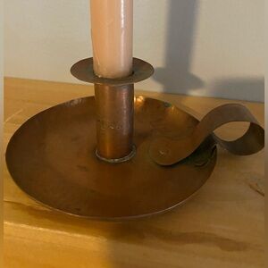 Antique hand-wrought copper chamber candlestick with a curved handle.